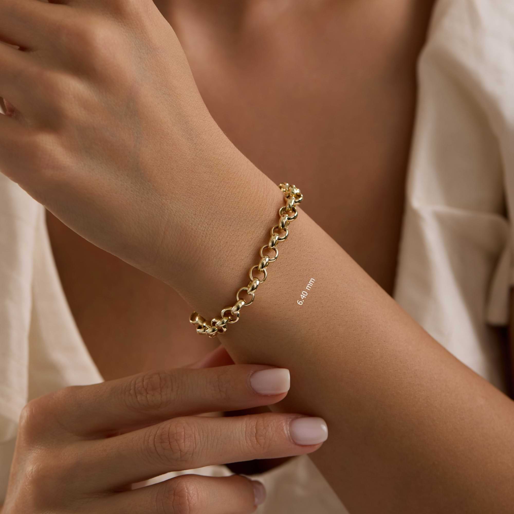 Gold 6.4mm rolo chain bracelet on a wrist with a neutral background