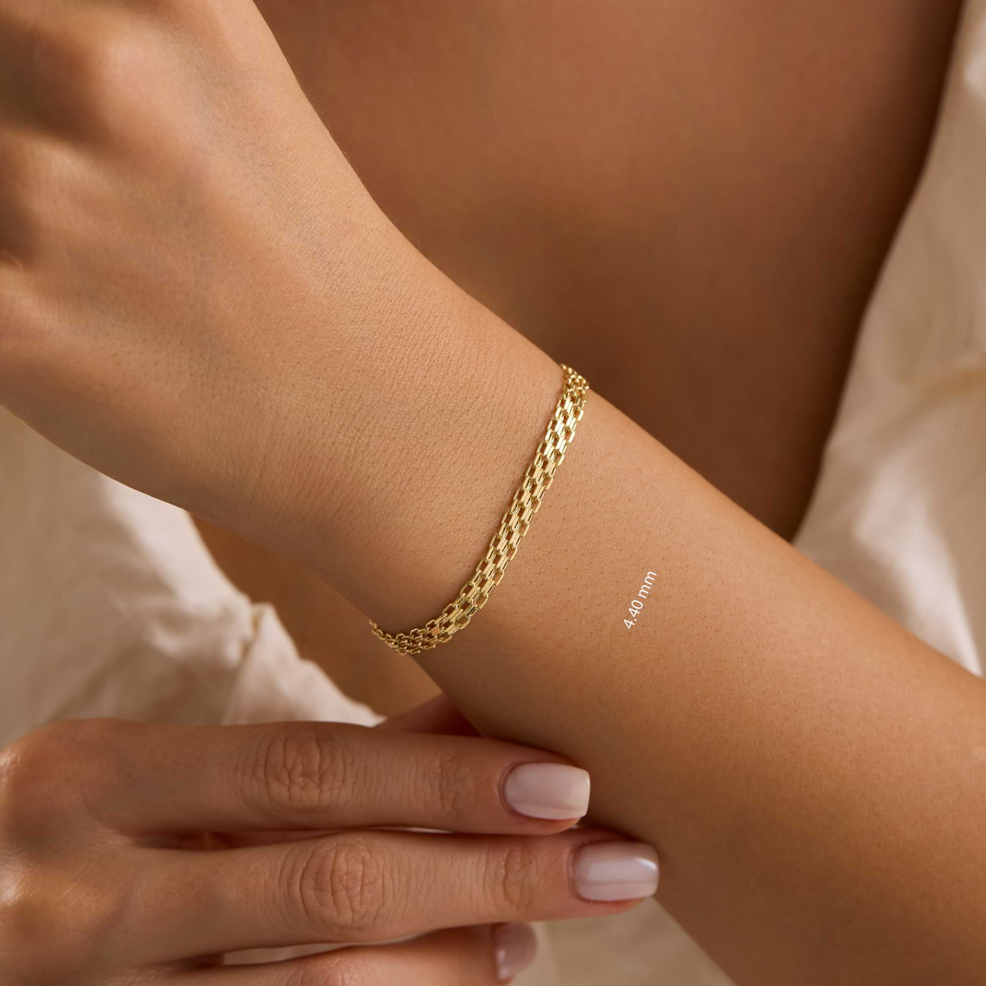 Gold 4.4mm bismarck chain bracelet on a wrist with a blurred background