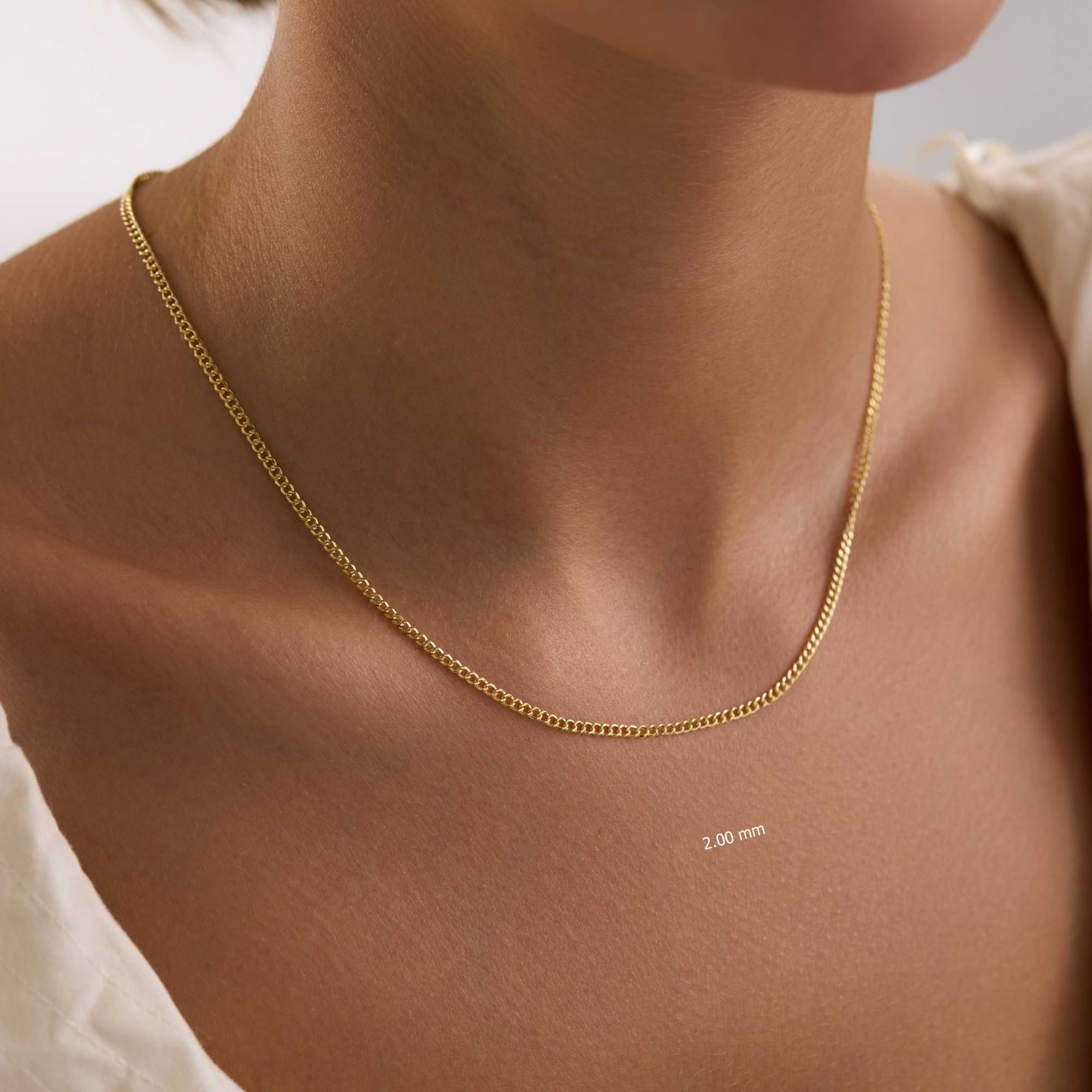 Gold 2mm curb chain necklace on a person's neck