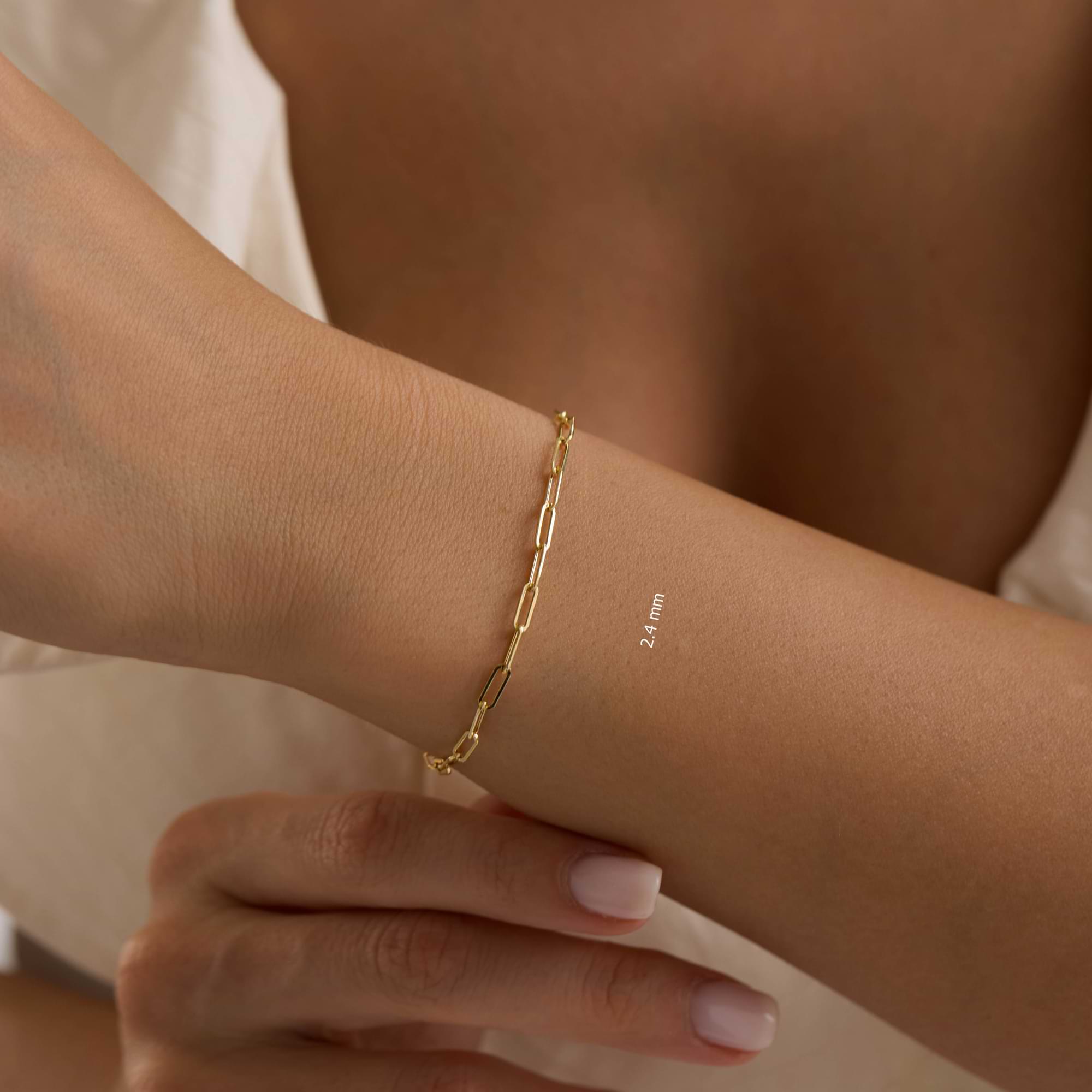 Gold 2.4mm paperclip chain bracelet on a woman's wrist