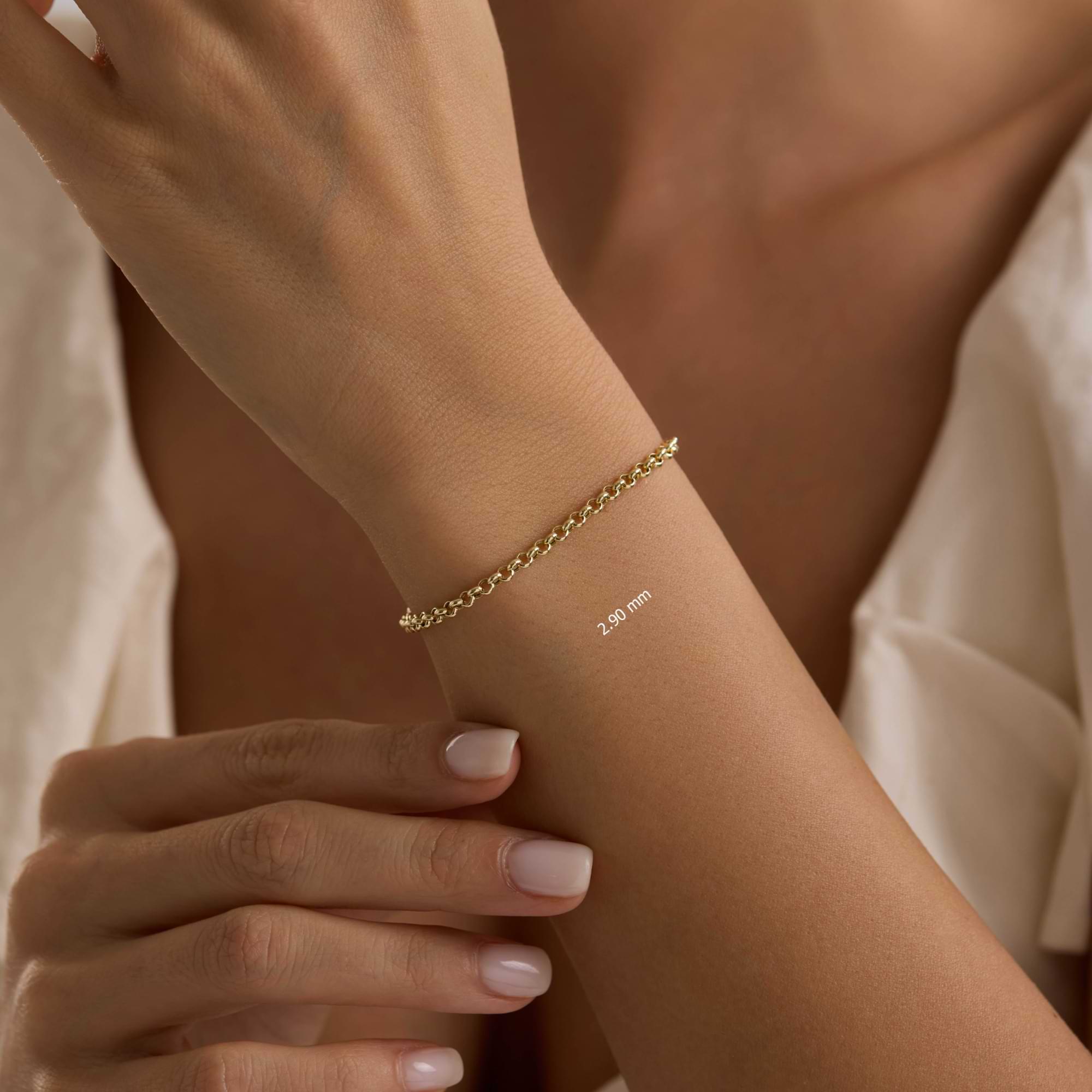 Gold 2.9mm rolo chain bracelet on a wrist with a neutral background