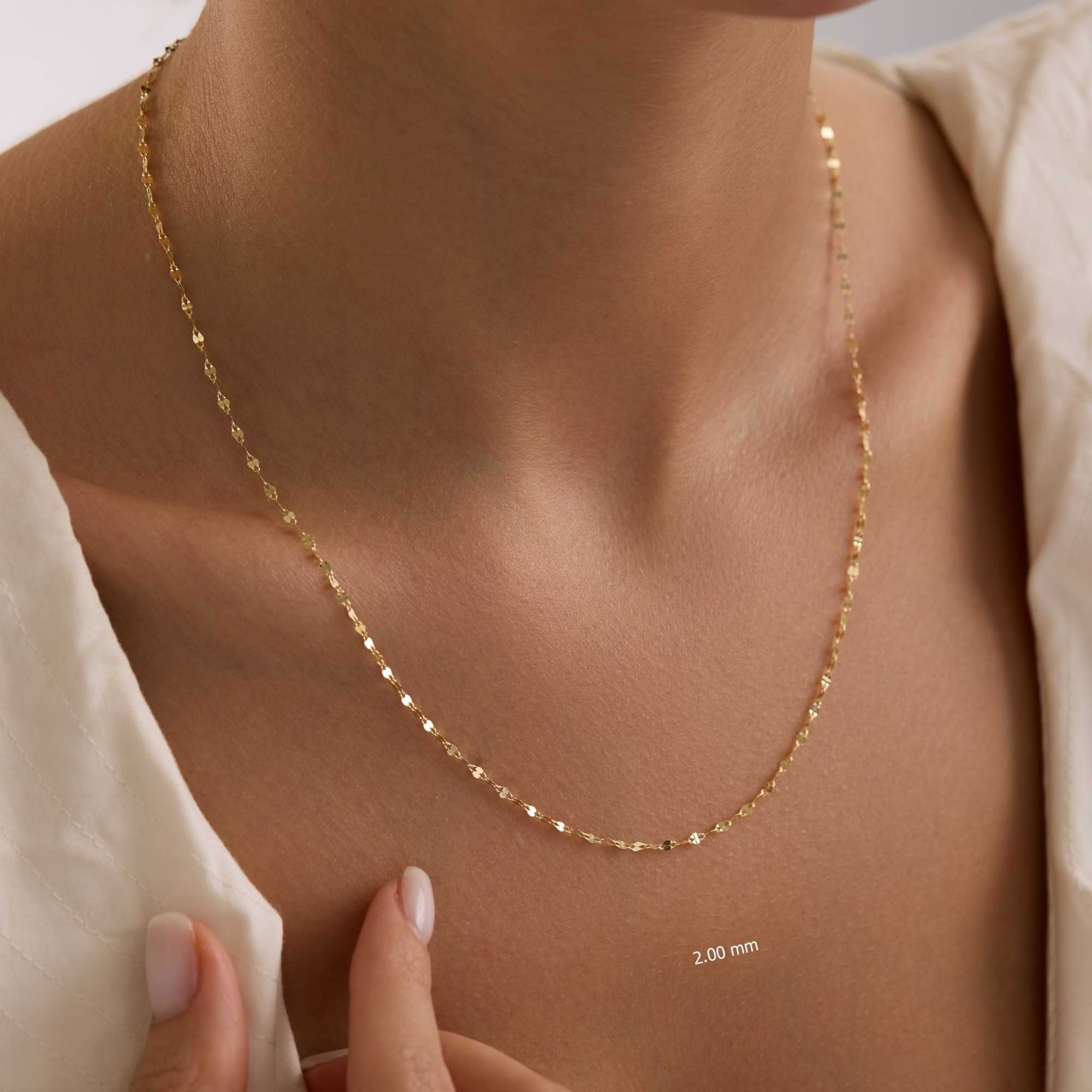 14k Gold 2mm sequin necklace on a person's neck with a neutral background