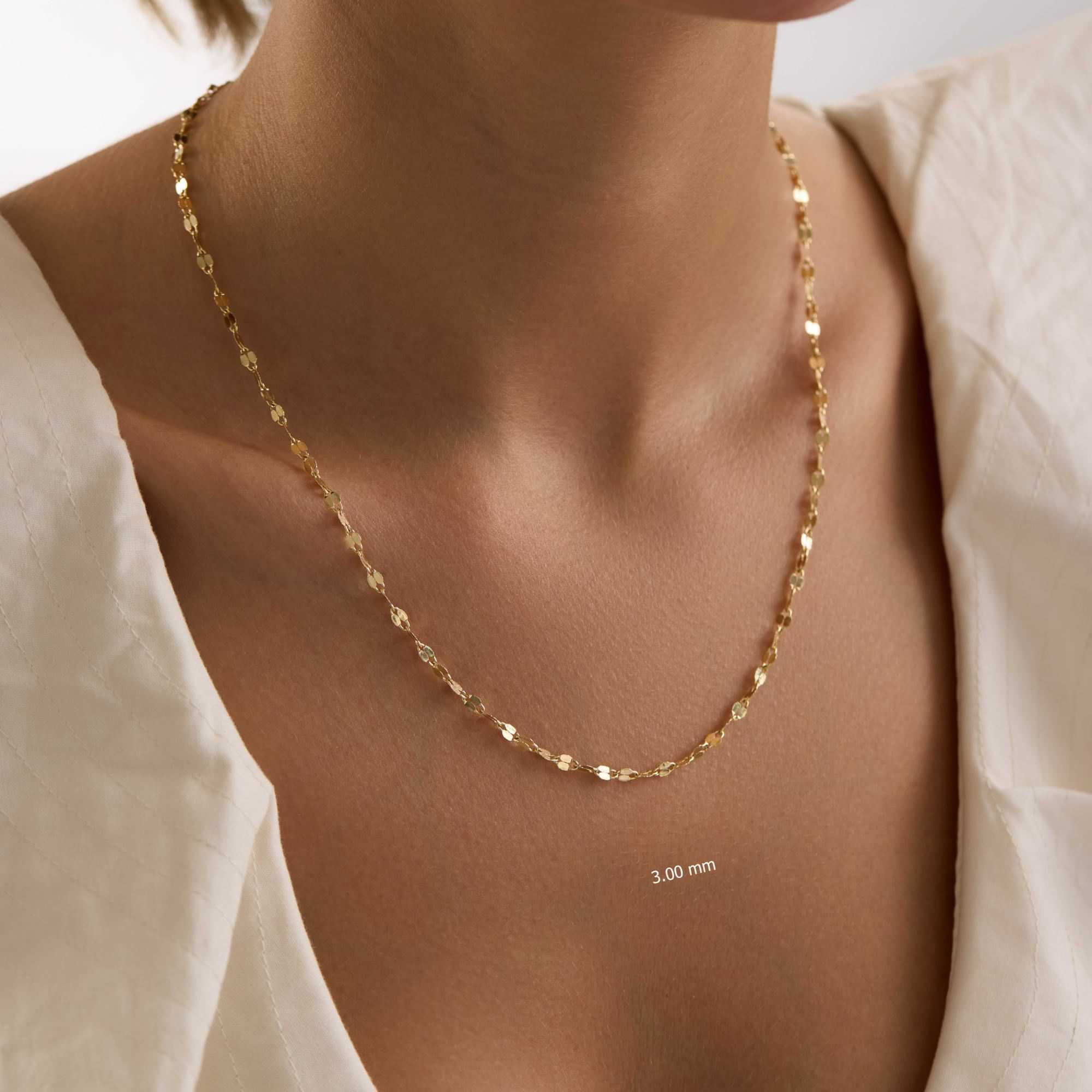 Gold sequin necklace on a person wearing a light-colored top