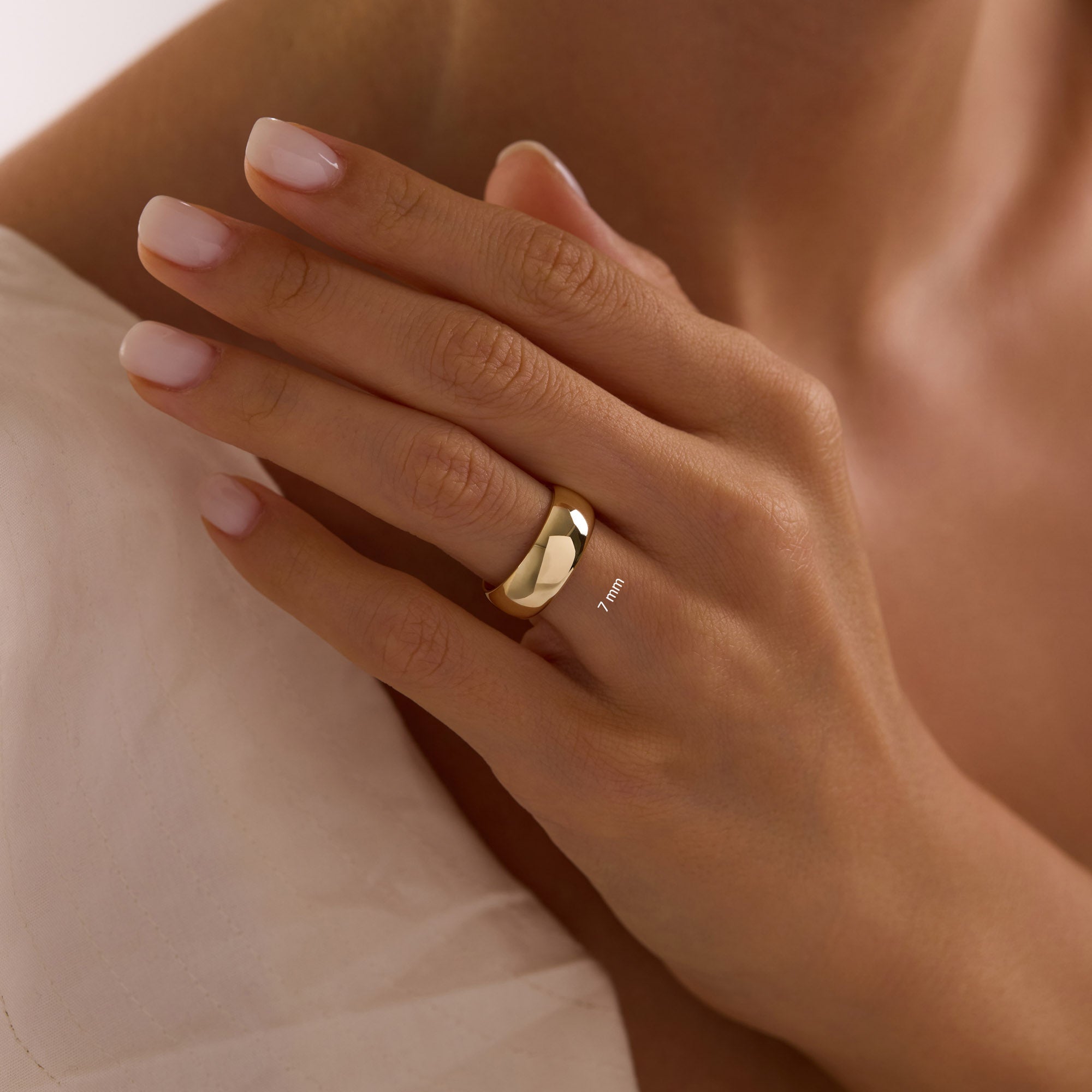 Close-up of hand wearing 14k solid yellow gold 7mm wedding band bold wide polished dome ring.