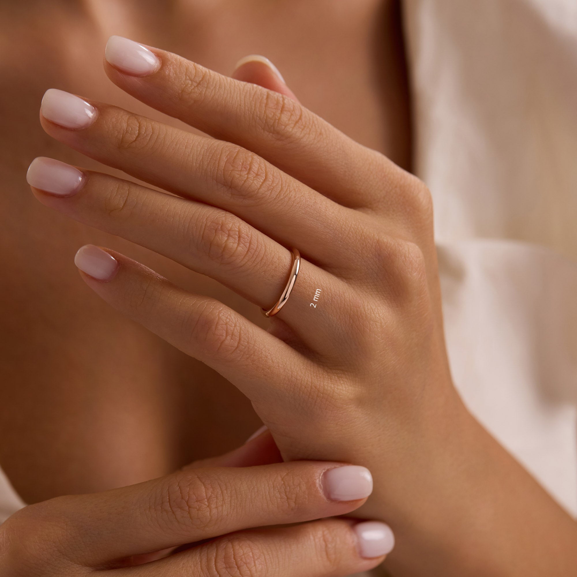 Close-up of hand wearing 14k solid rose gold 2mm wedding band, simple thin stacking ring