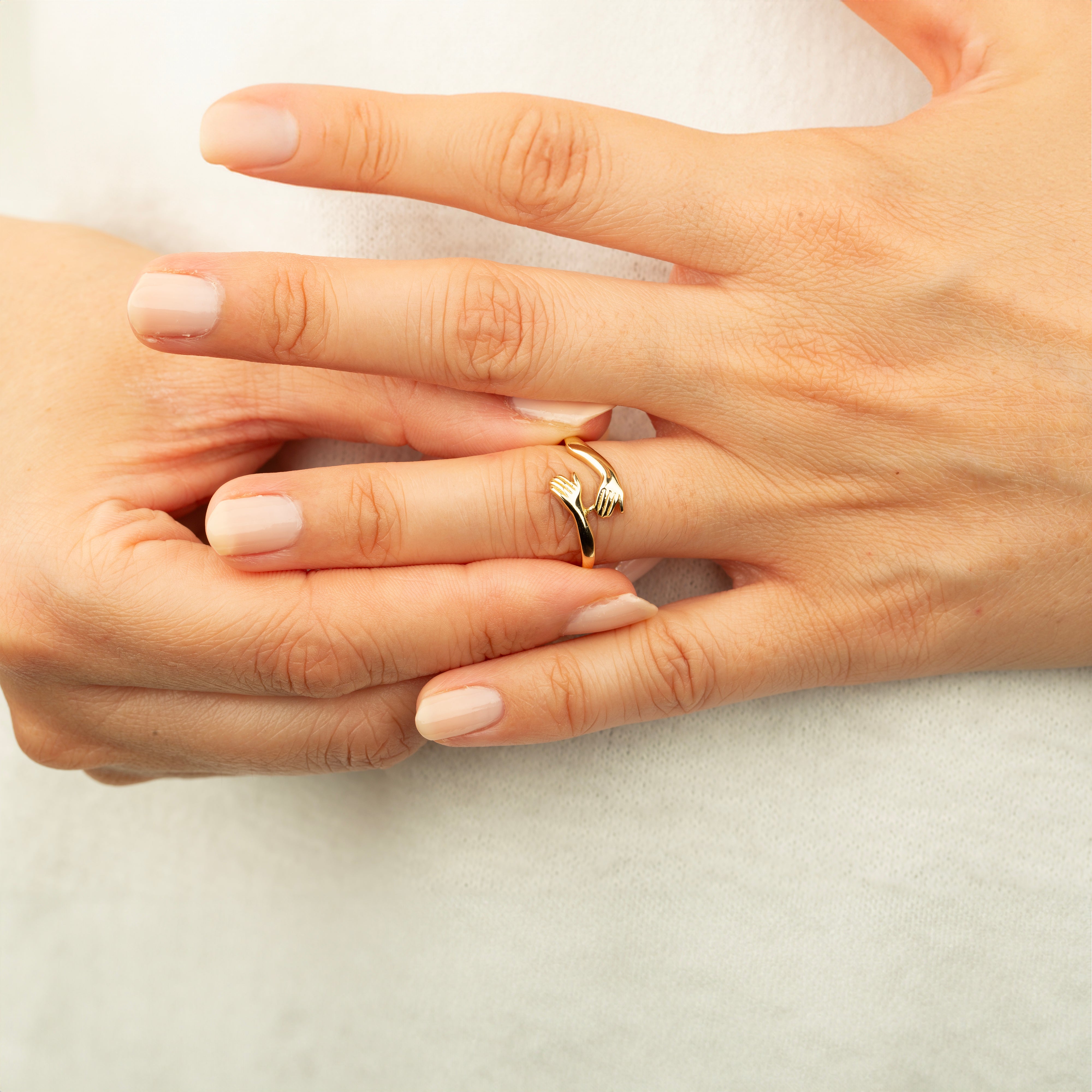 woman wearing 14k gold hug ring on fingers with white background