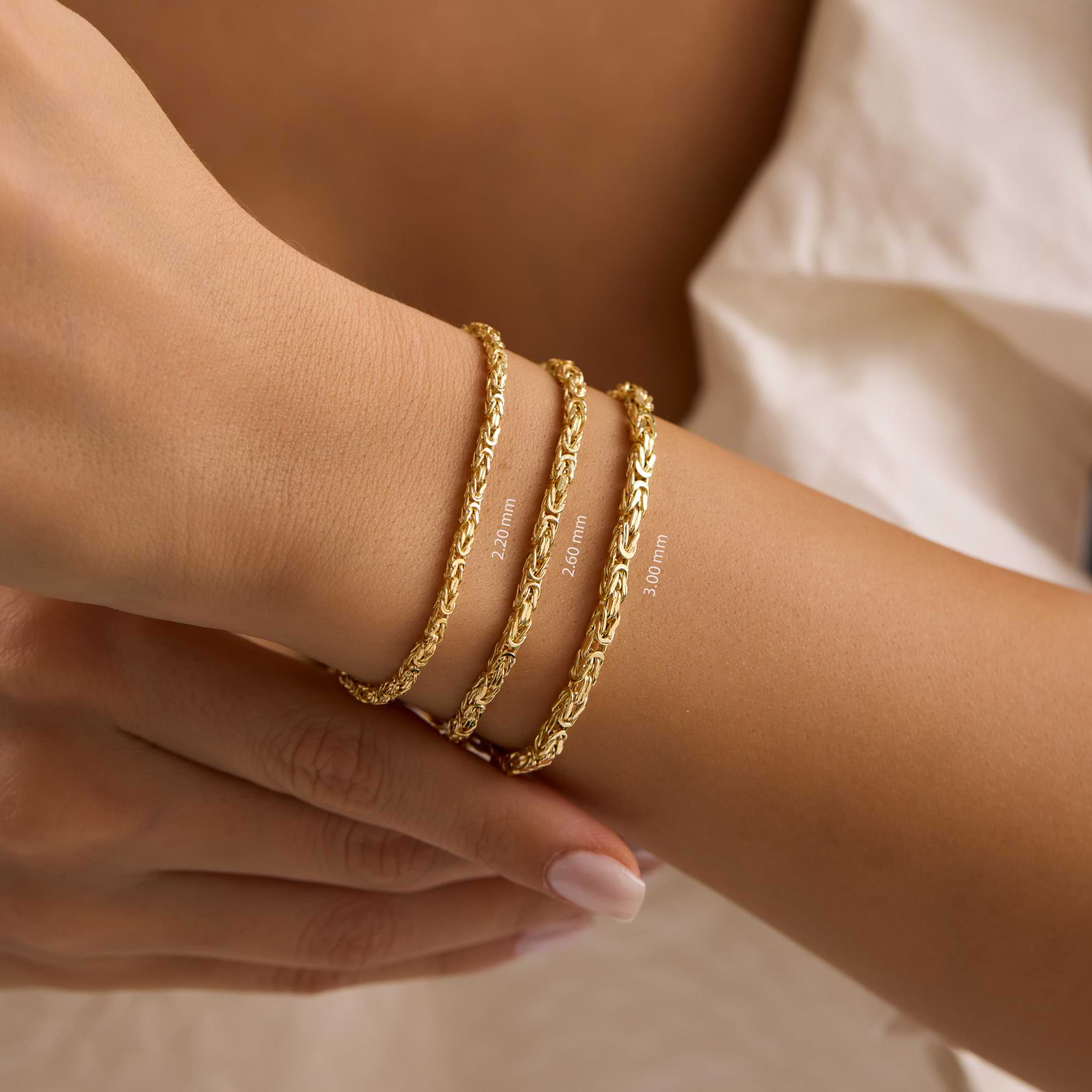three Gold byzantine chain bracelets on a wrist of woman