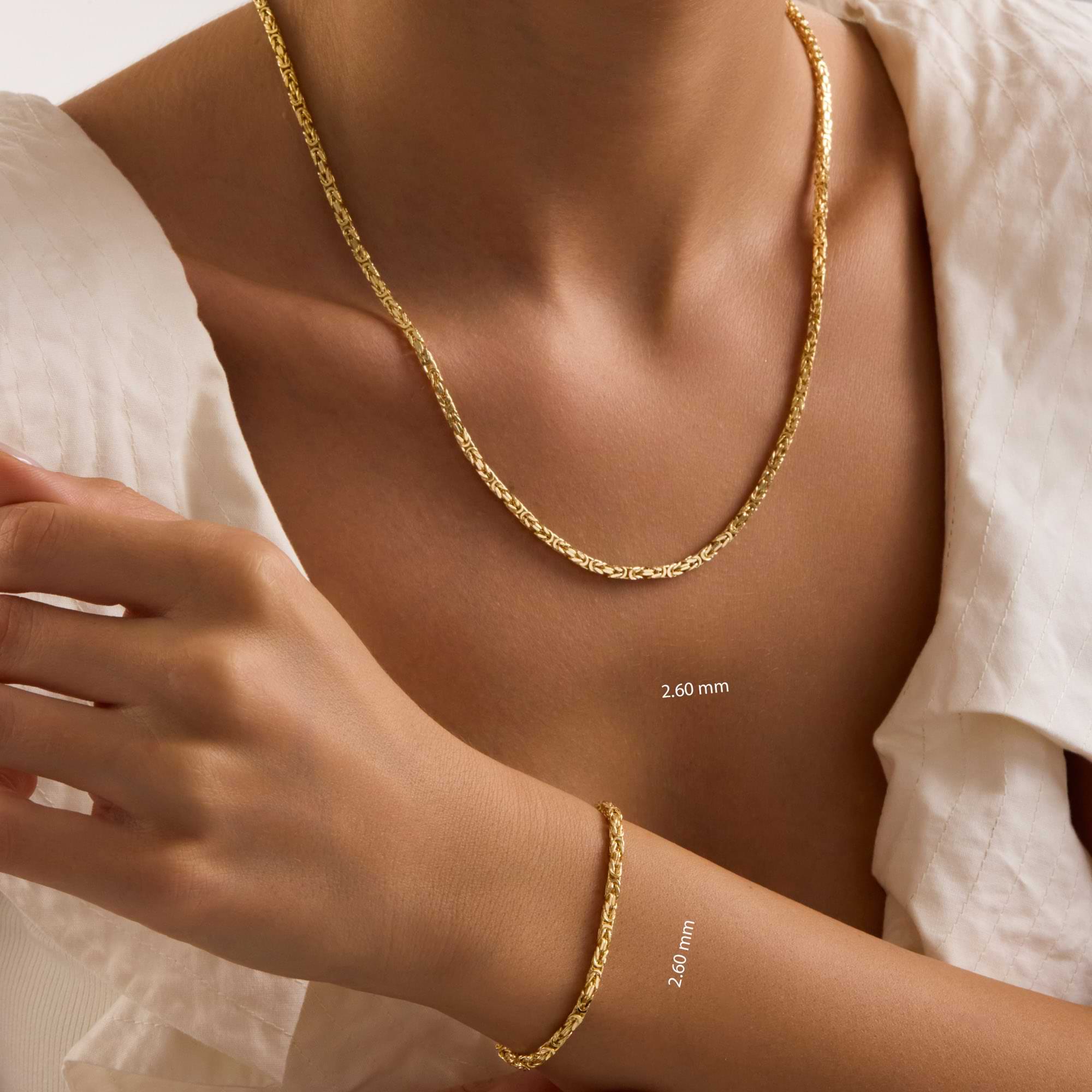 Gold 2.6mm byzantine necklace and bracelet on a person wearing a white top