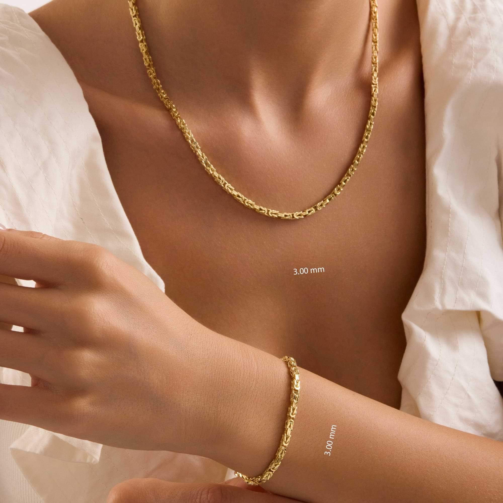 Gold 3mm byzantine chain necklace and bracelet on a person wearing a white shirt.