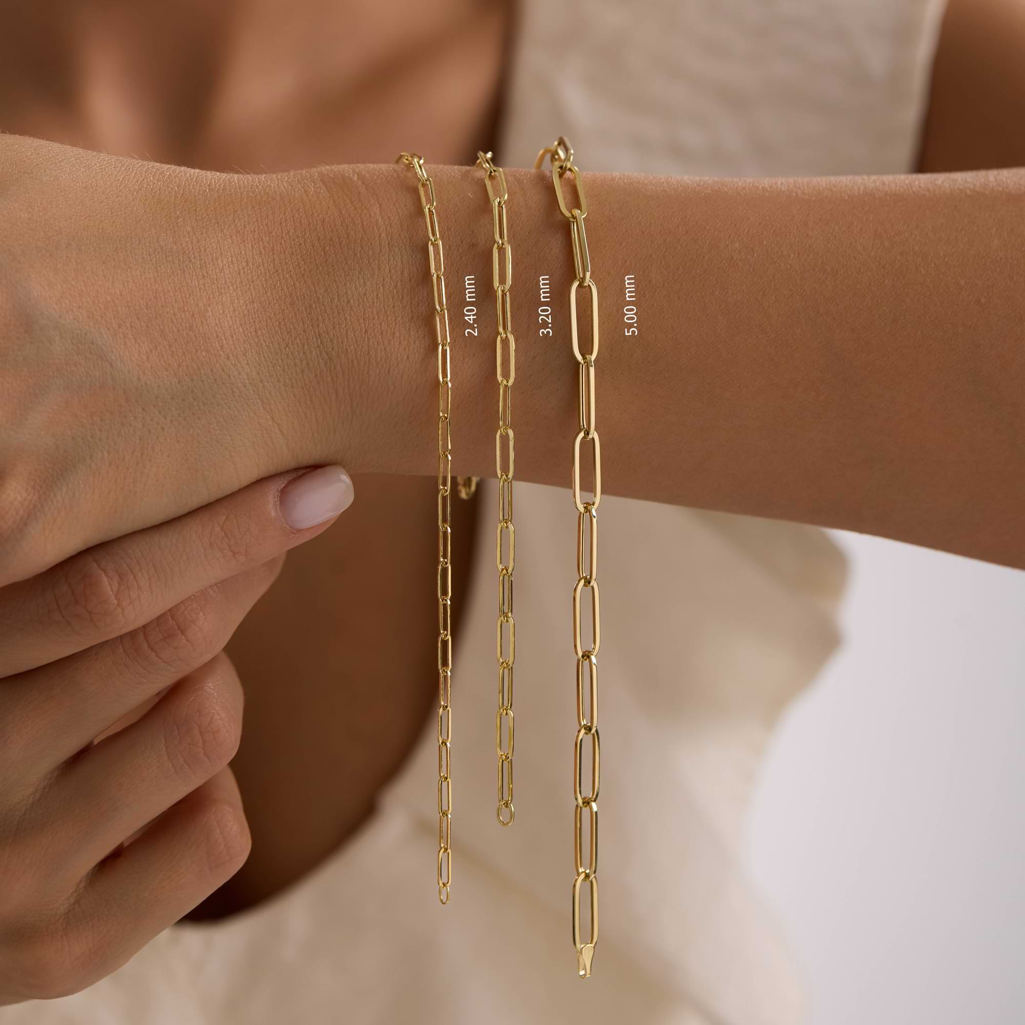 Gold paperclip chain bracelets on a person's wrist with measurements displayed.